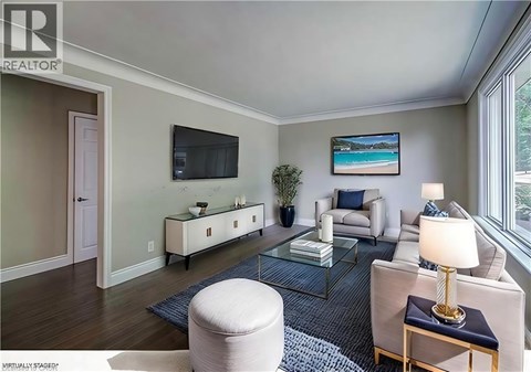 A living room with a white couch, a glass coffee table, and a painting on the wall.