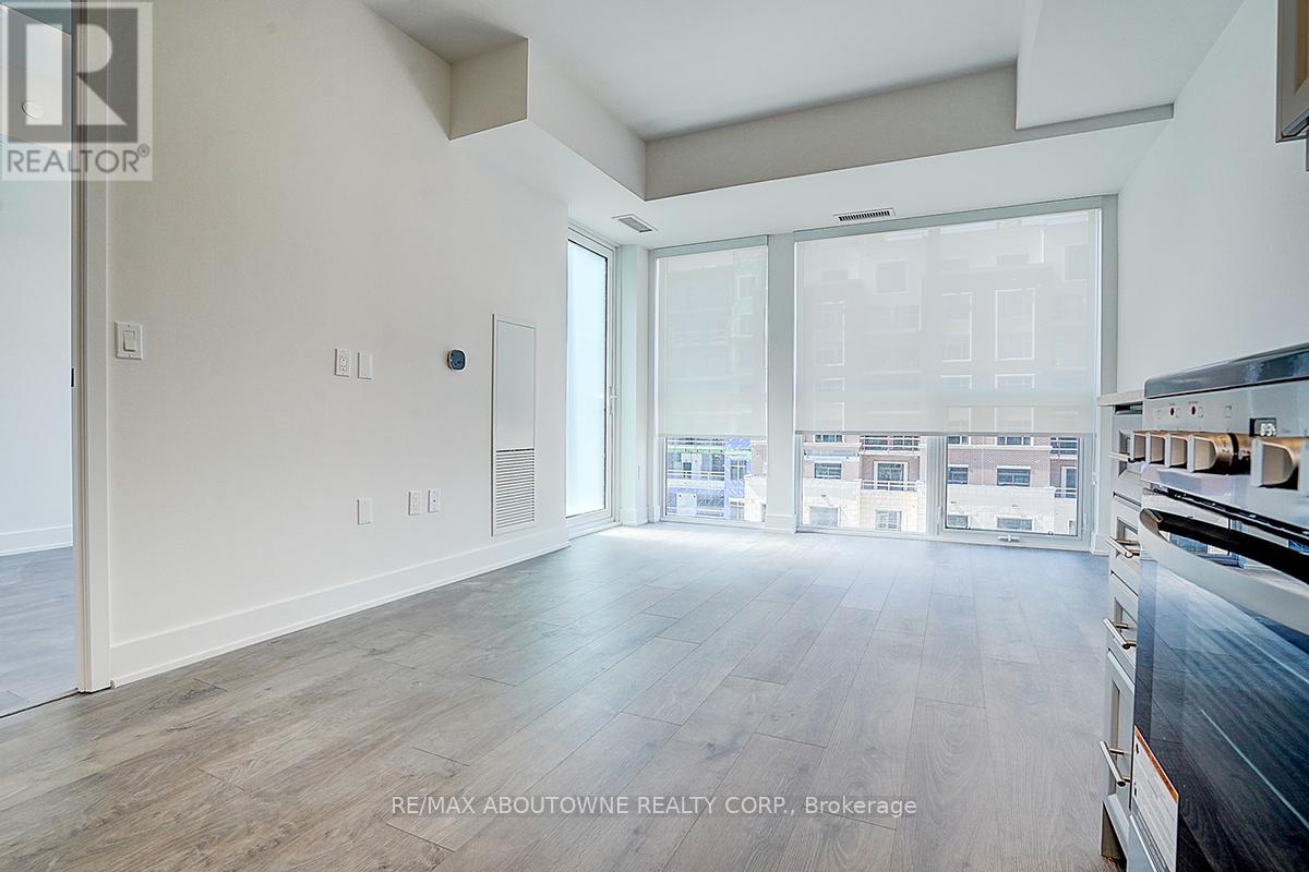 A spacious room with wooden flooring and large windows.
