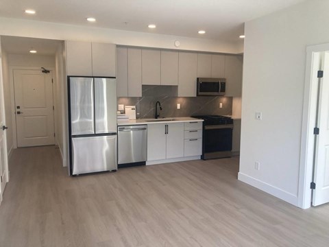 A kitchen with a refrigerator, dishwasher, and oven.