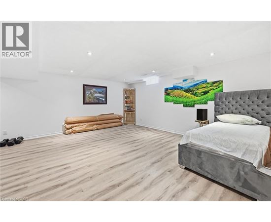 A bedroom with a large bed and a painting on the wall.