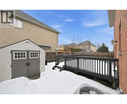 A snow-covered ground with a wooden fence and a building in the background.