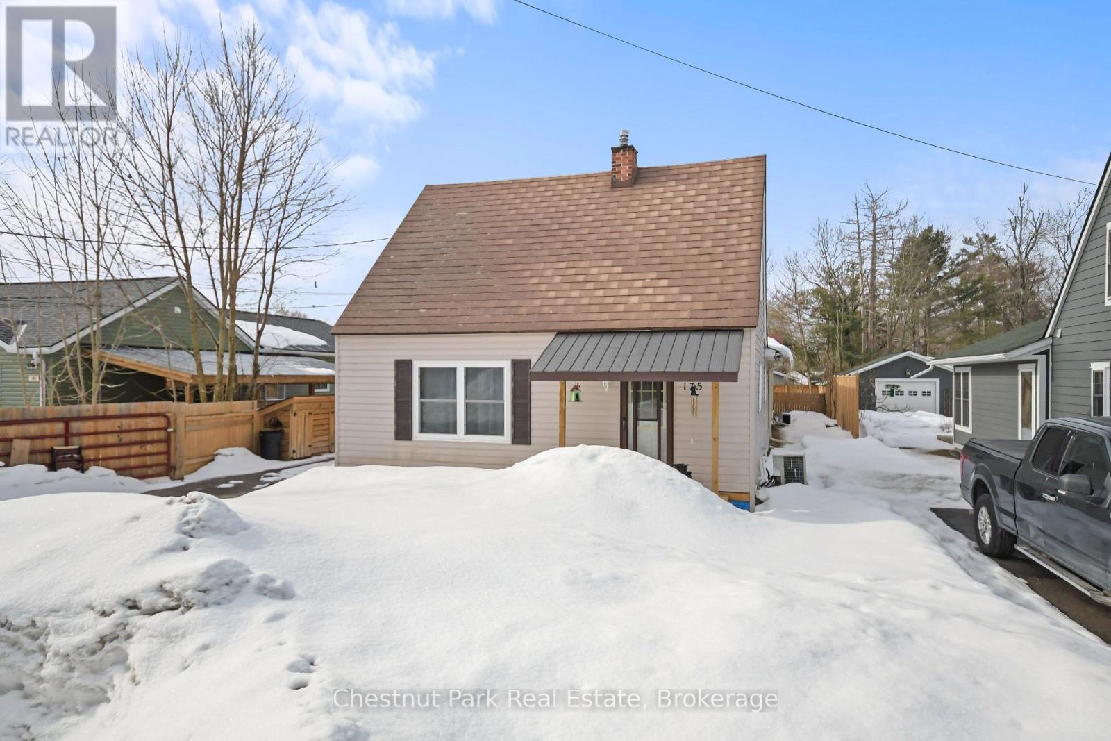 A house with a brown roof and a white garage door is surrounded by snow.