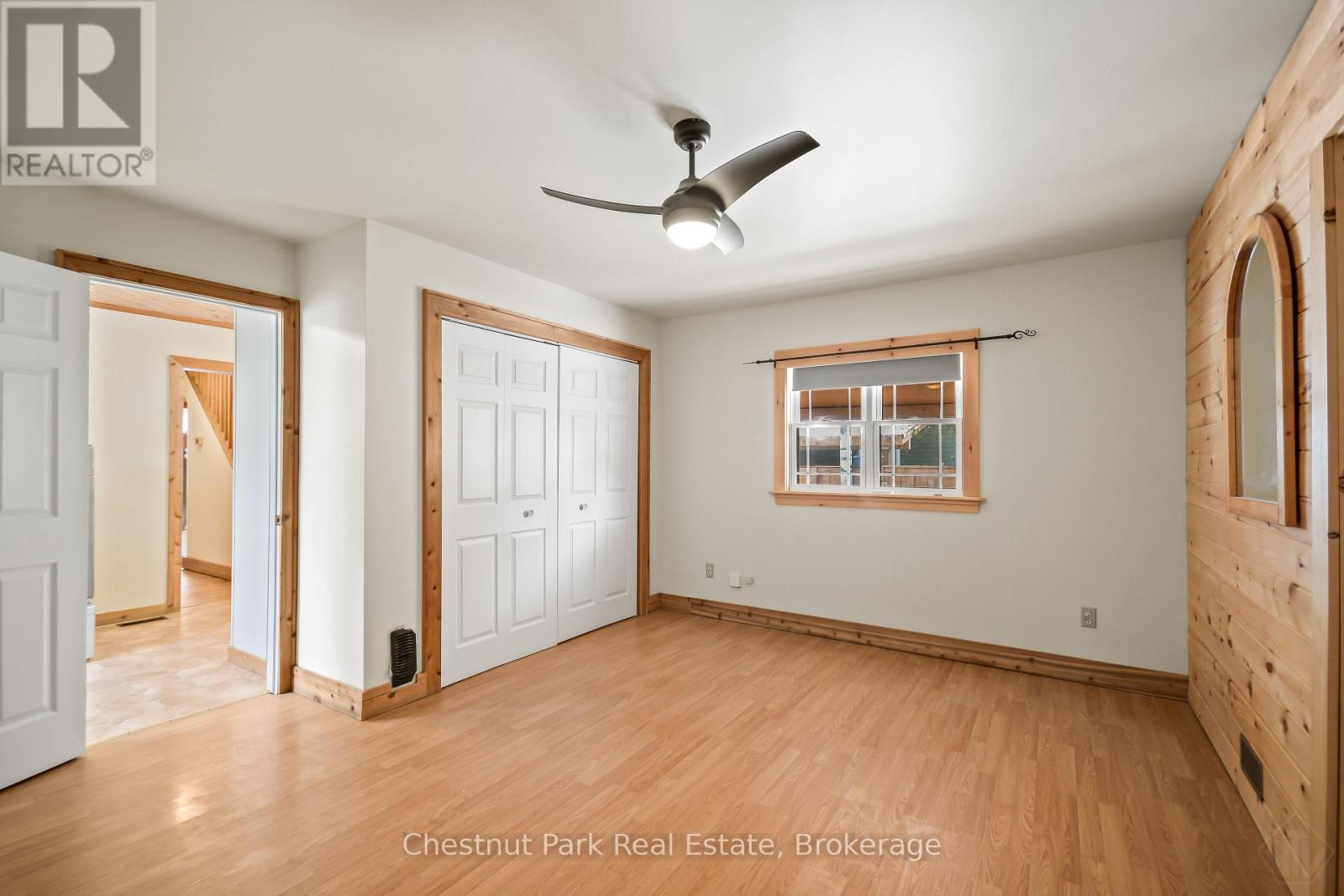 A room with a ceiling fan and a window with a view of a building outside.