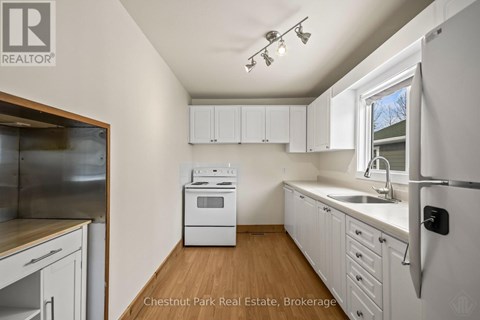 A kitchen with white cabinets and a stainless steel refrigerator.