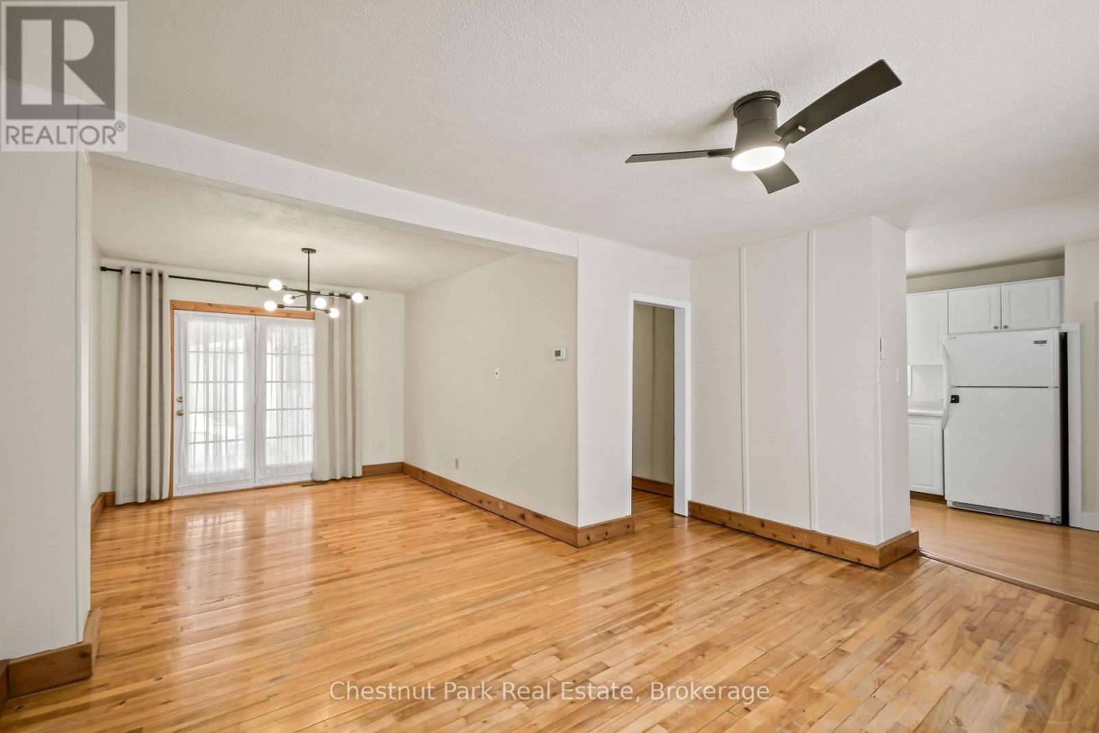 A spacious room with wood flooring and a ceiling fan.