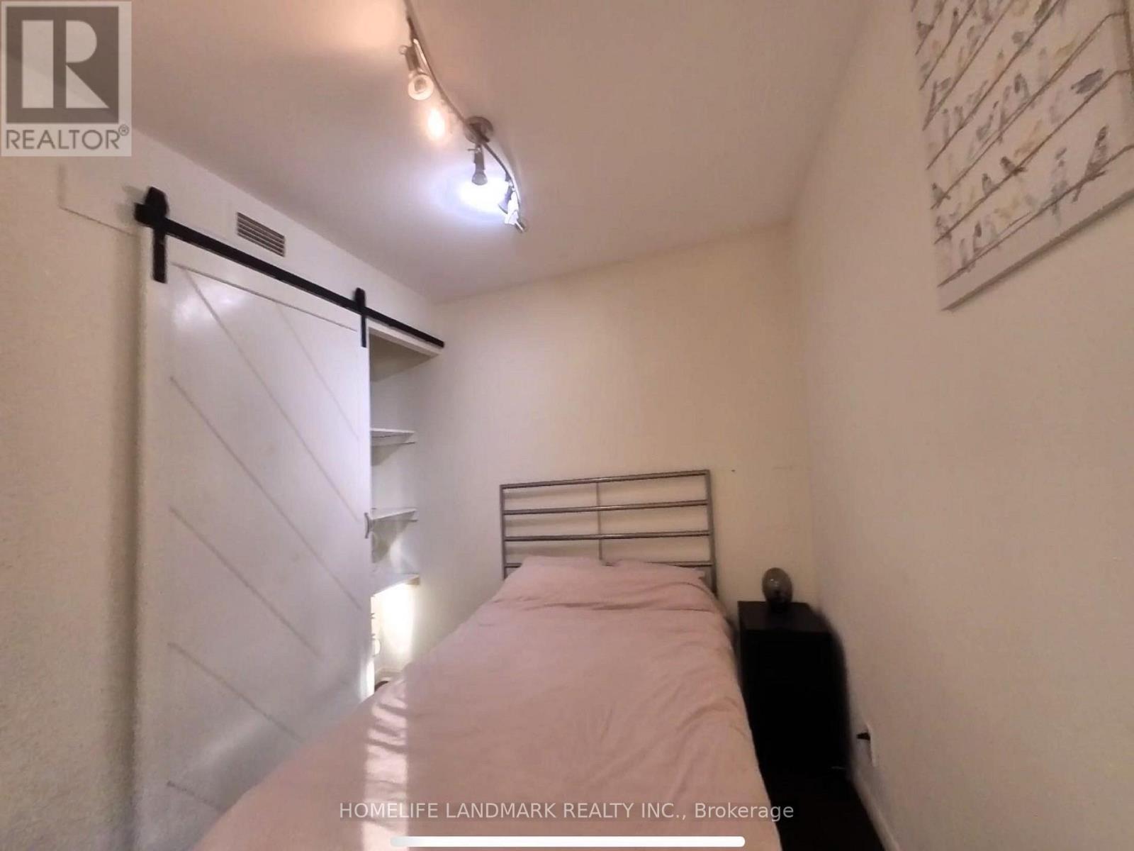 A bedroom with a bed, a nightstand, and a wall hanging.