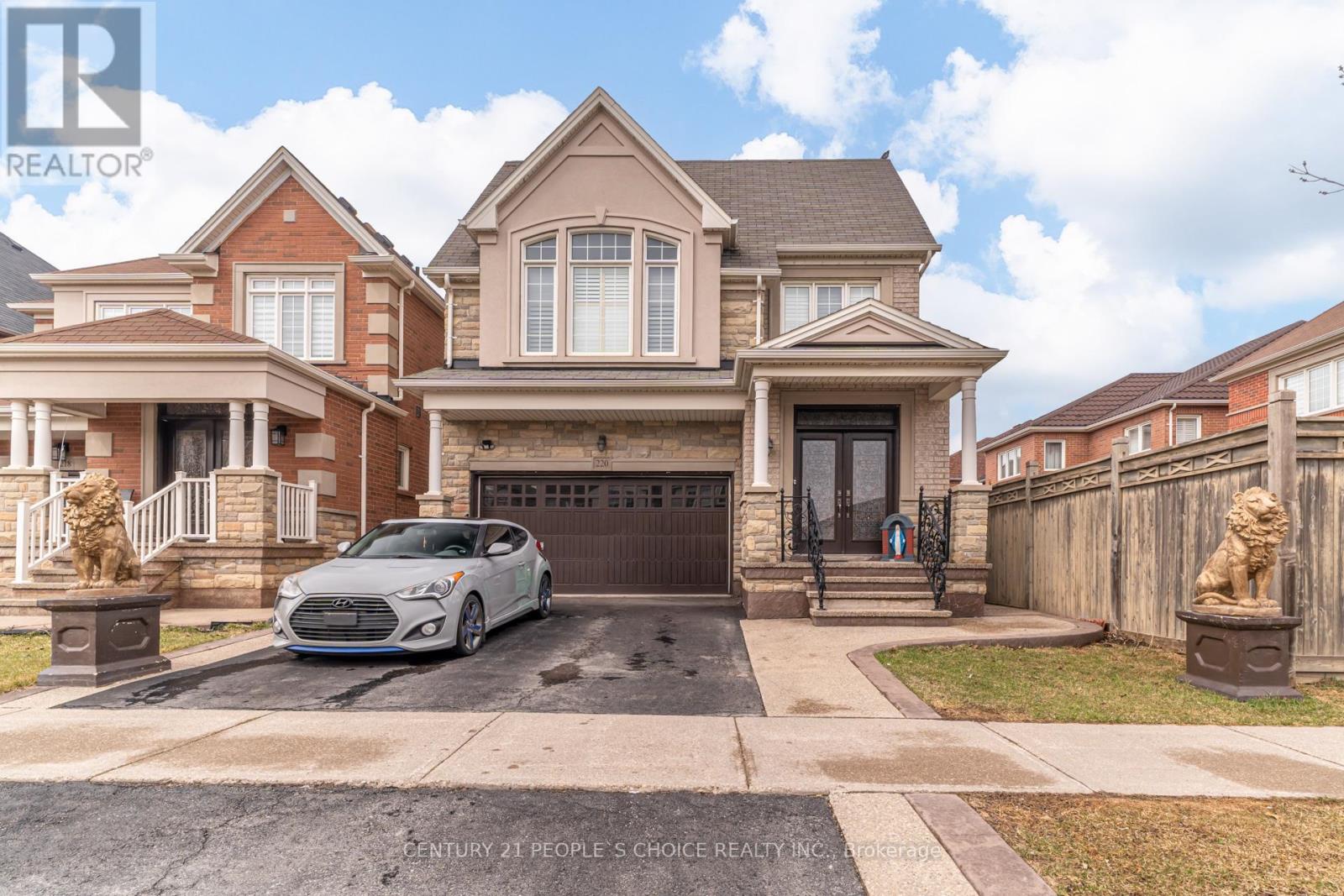 A silver car is parked in front of a brick house.