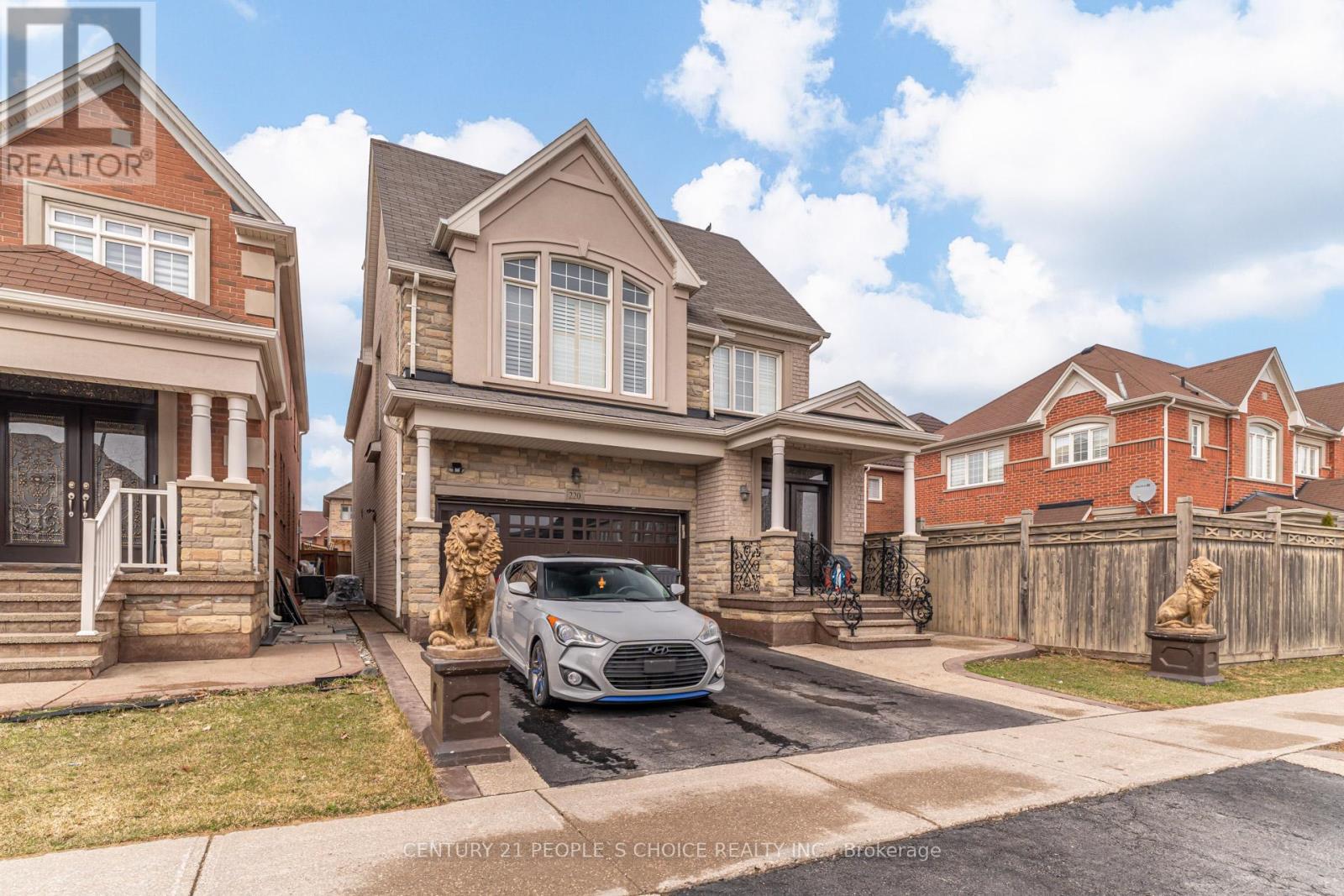 A silver car is parked in front of a house with a garage.