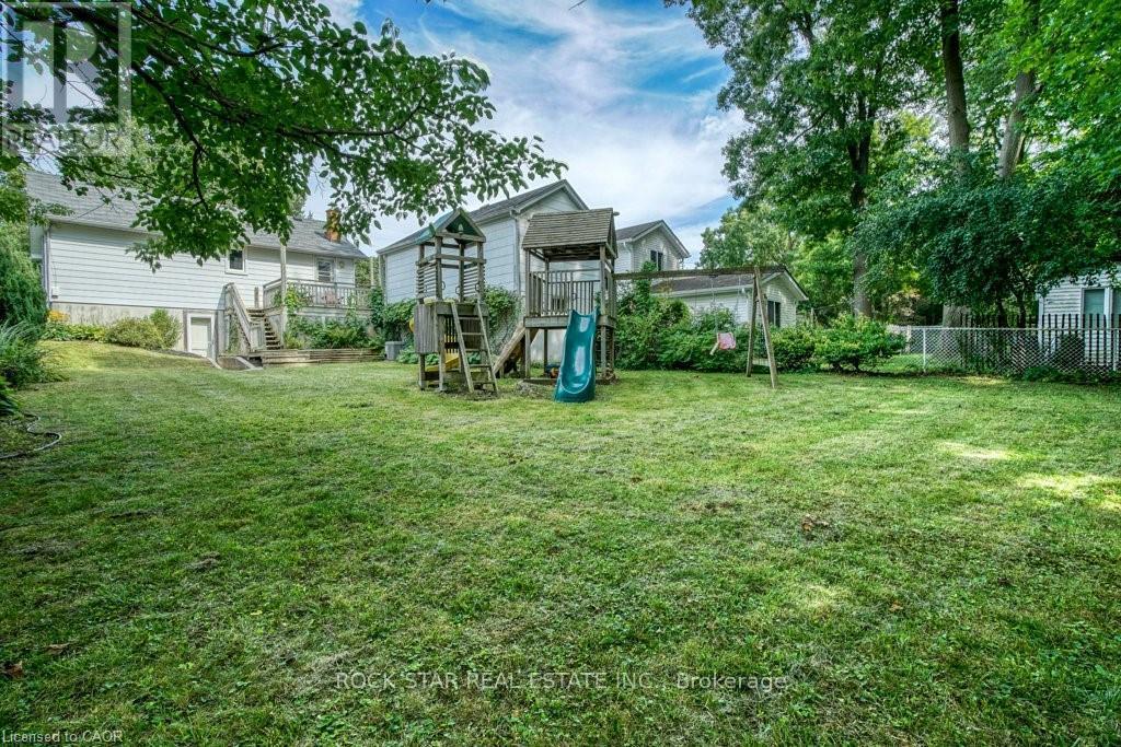 A backyard with a playground and a white house.