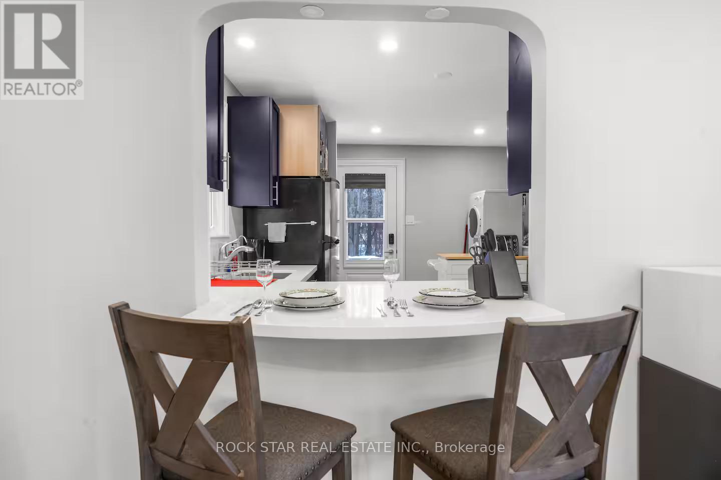 A dining room with a white table and two wooden chairs.
