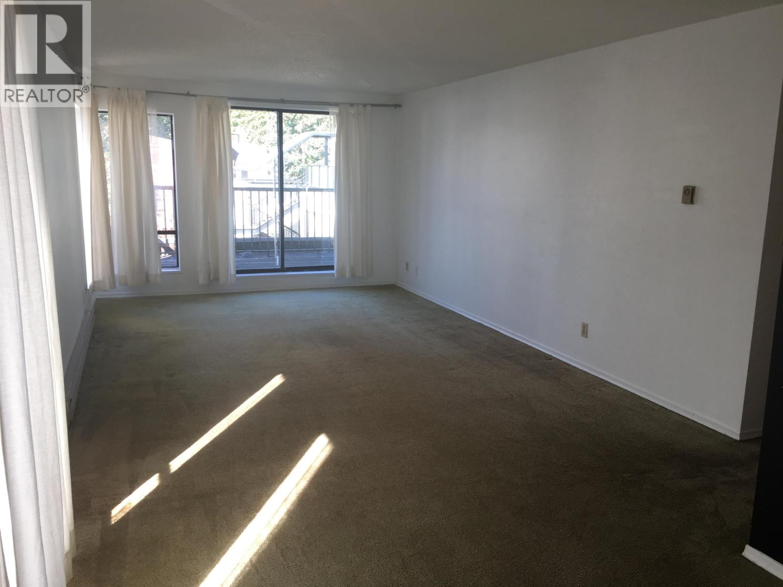 A spacious room with a large window and a sliding glass door.