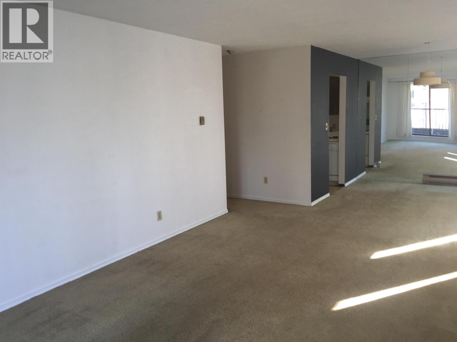 A large empty room with a carpeted floor and white walls.