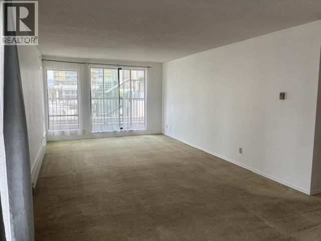 A room with a carpeted floor and a window with curtains.