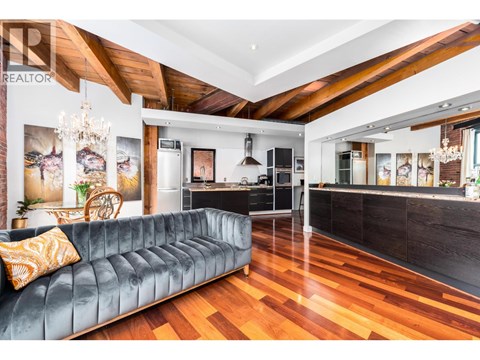 A modern living room with a black couch and wooden floors.