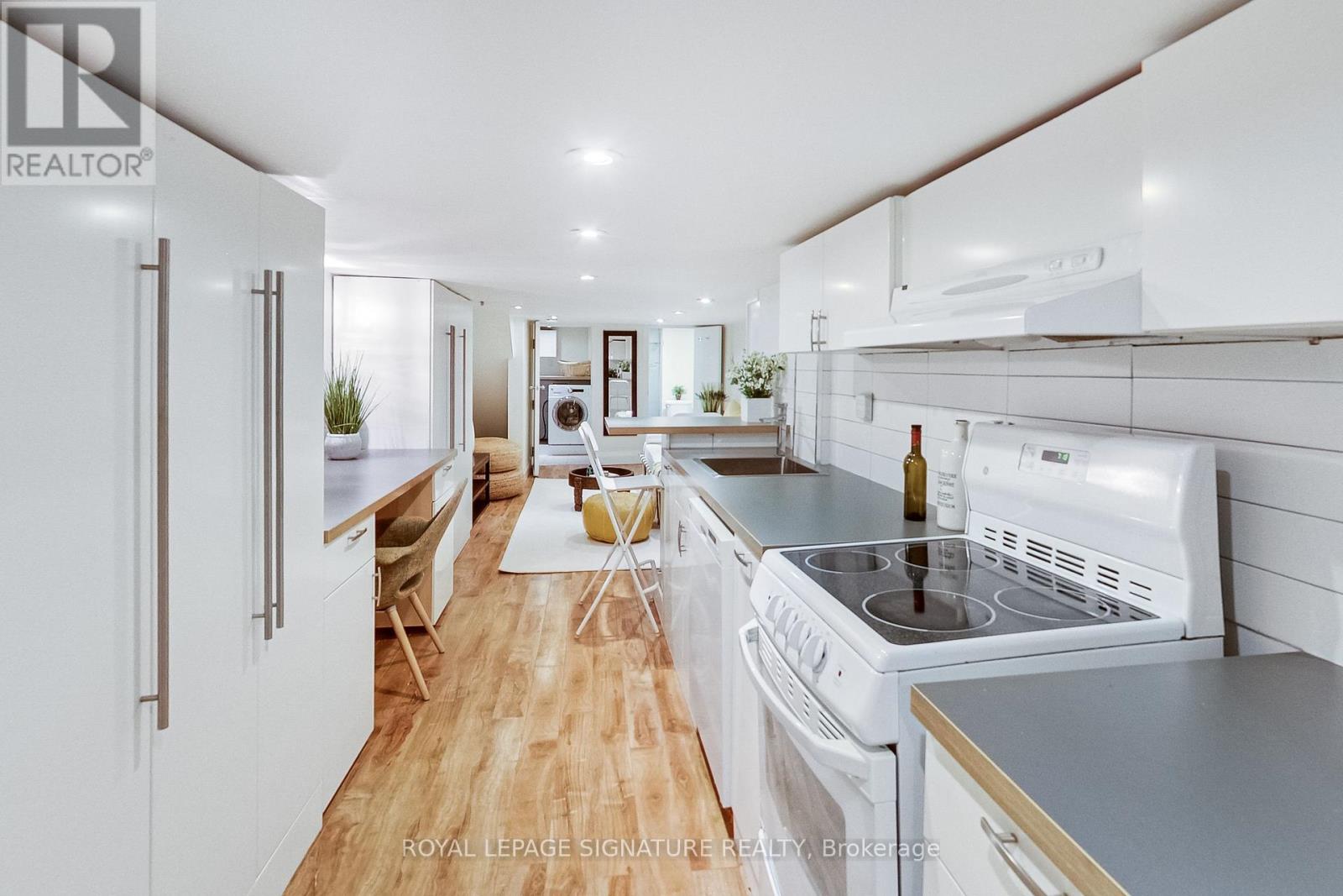 A modern kitchen with white appliances and wooden floors.