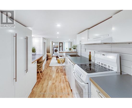 A modern kitchen with white appliances and wooden floors.
