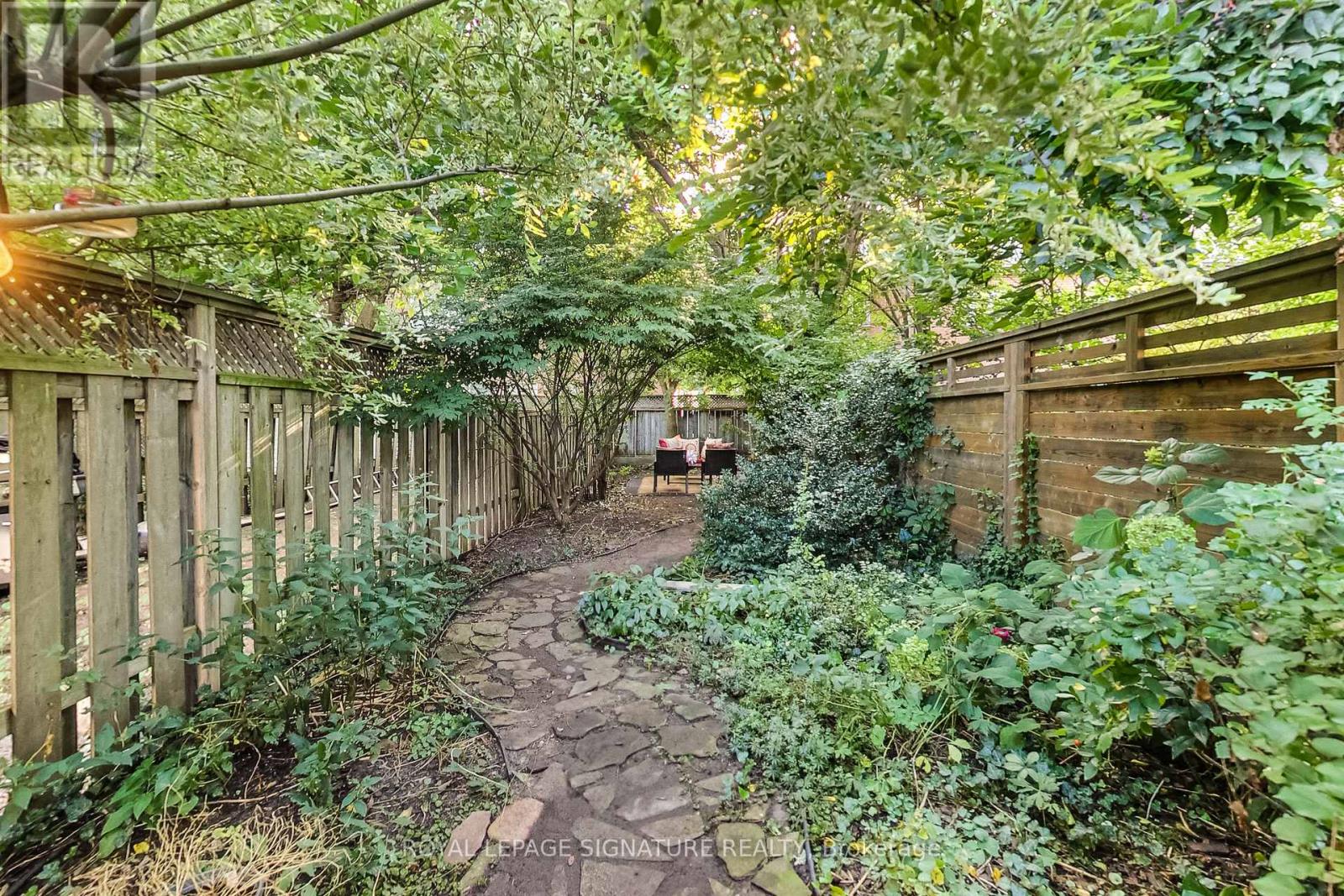 A garden pathway surrounded by green plants and trees.