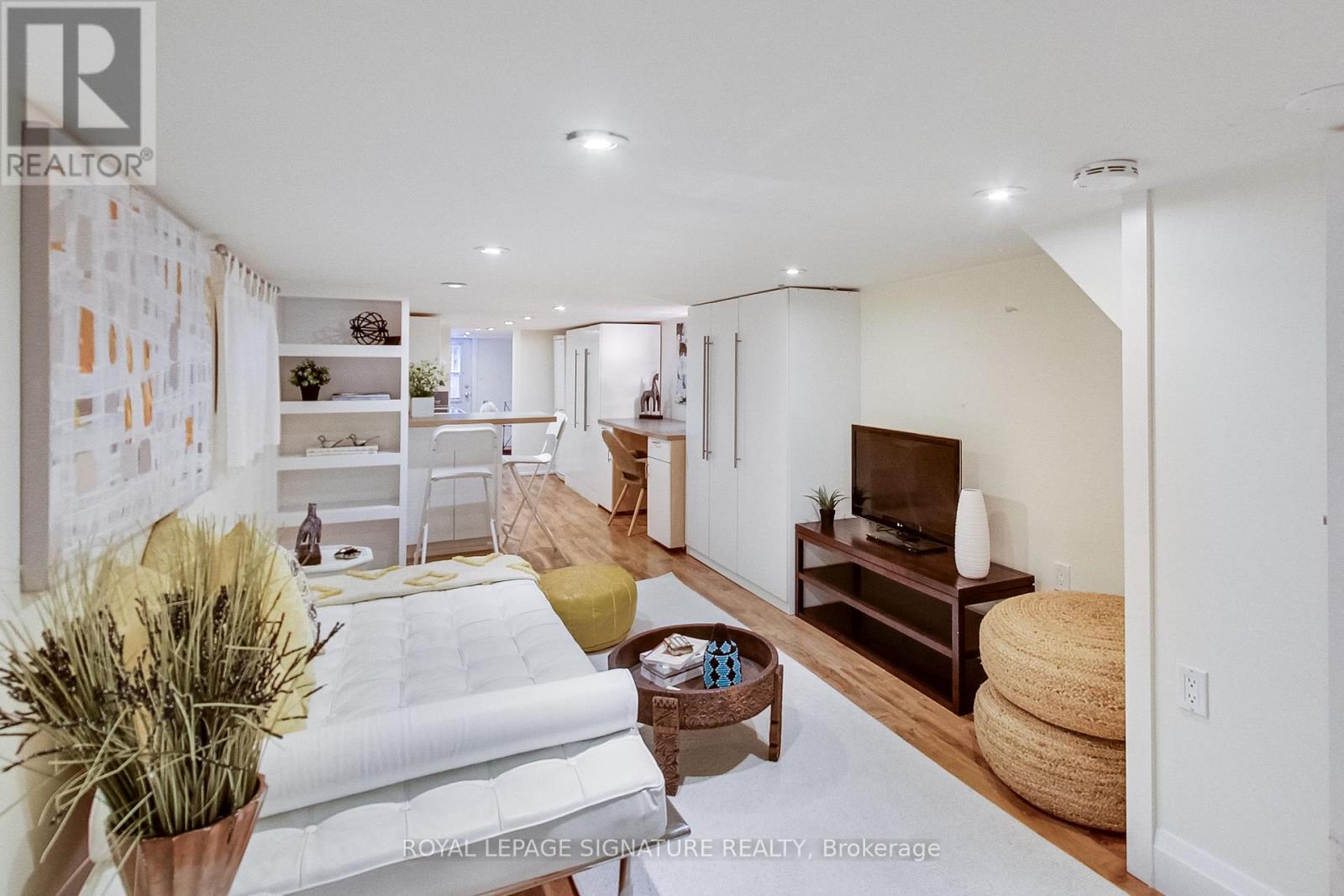 A well-lit, modern living room with a white sofa and a television.