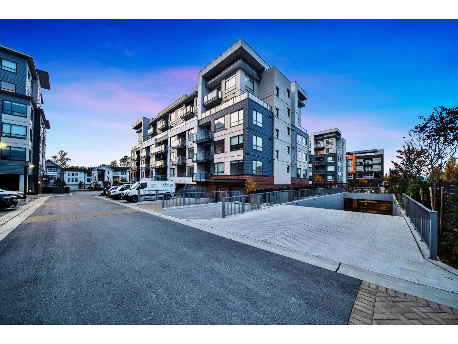 A modern apartment complex with a parking lot in front.