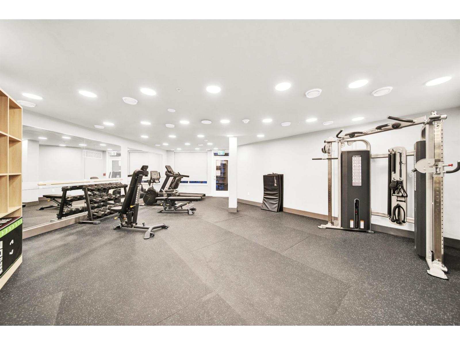 A gym with a variety of equipment including treadmills, weights, and exercise machines.