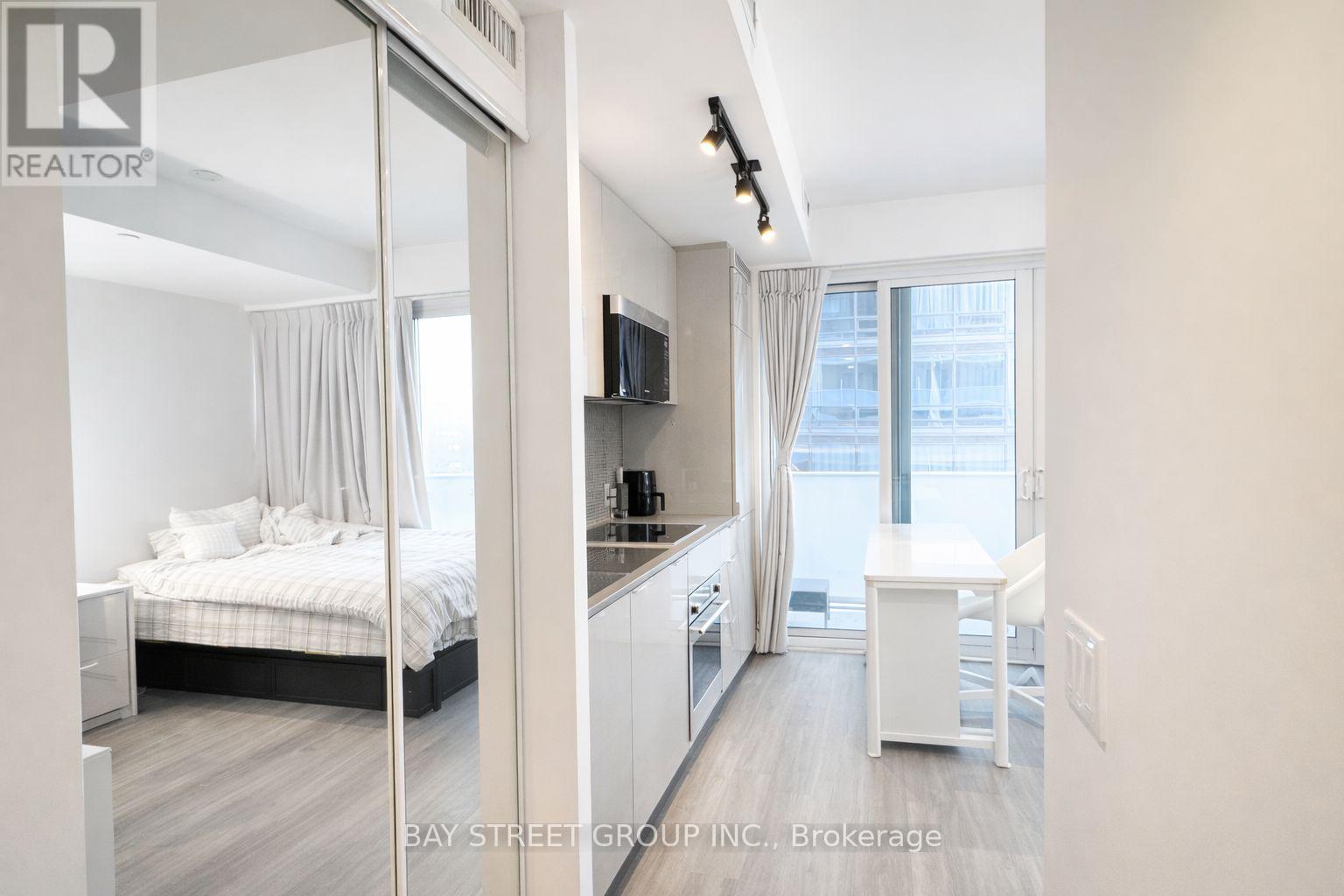 A bedroom with a bed, a TV, and a window with curtains.