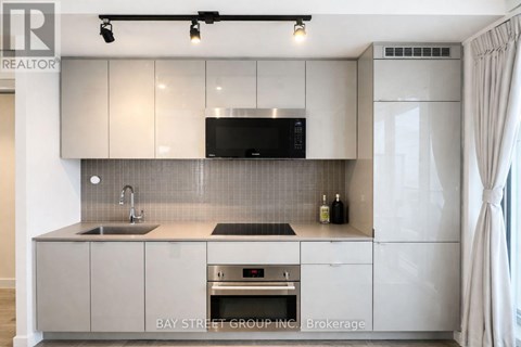 A modern kitchen with a sink, stove, and refrigerator.