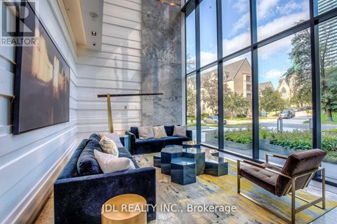 A living room with a couch, chair, and a large window showing an outdoor view.