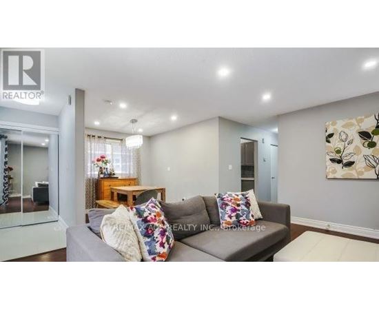 A living room with a grey couch and a painting on the wall.