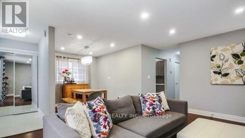 A living room with a grey couch and a painting on the wall.