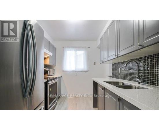 A kitchen with a stainless steel refrigerator and a sink with a faucet.