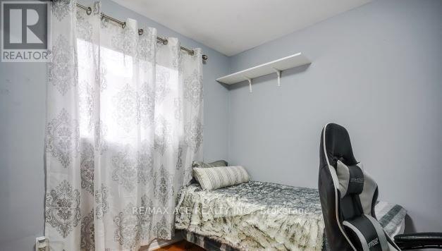A bedroom with a bed, chair, and window with curtains.