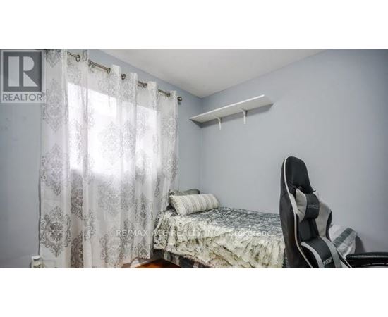 A bedroom with a bed, chair, and window with curtains.