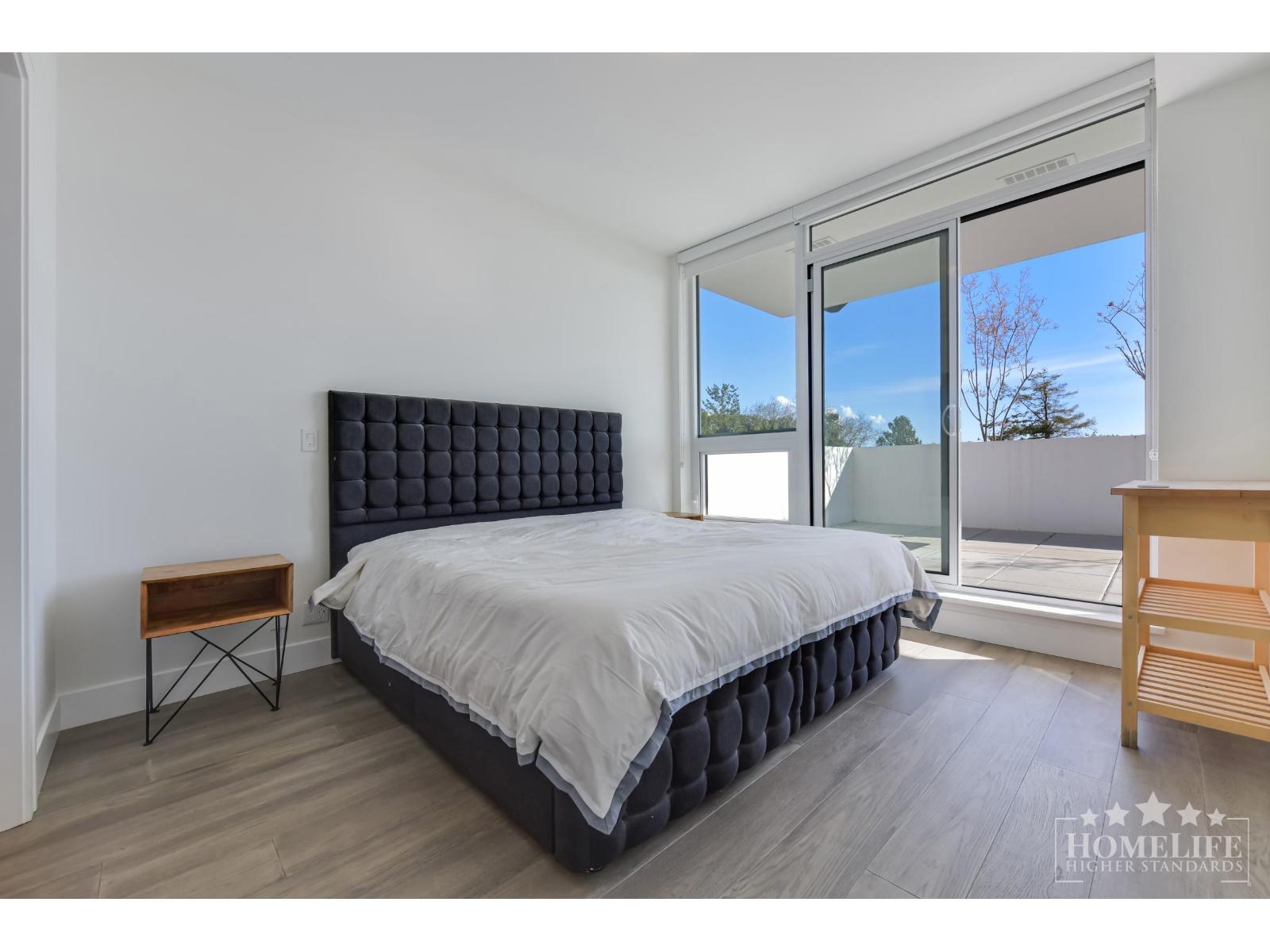 A bedroom with a large bed and a wooden nightstand.