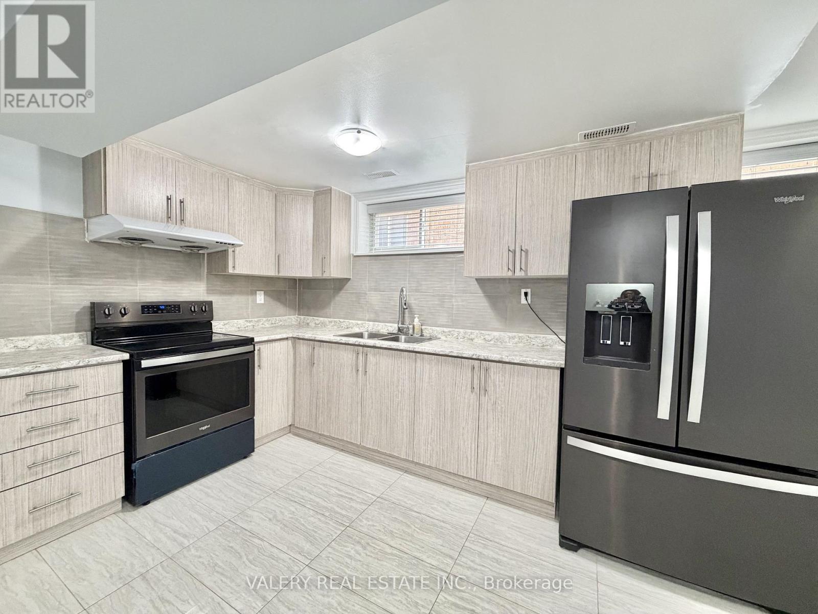 A kitchen with a stainless steel refrigerator and a stove top oven.