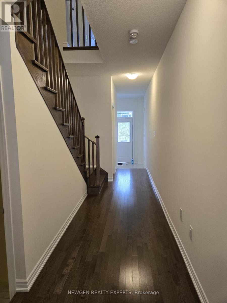 A long hallway with a staircase on the left and a door at the end.