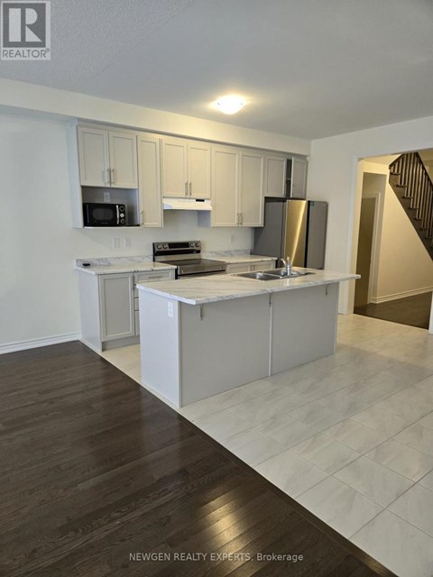A kitchen with white cabinets and a wooden floor.