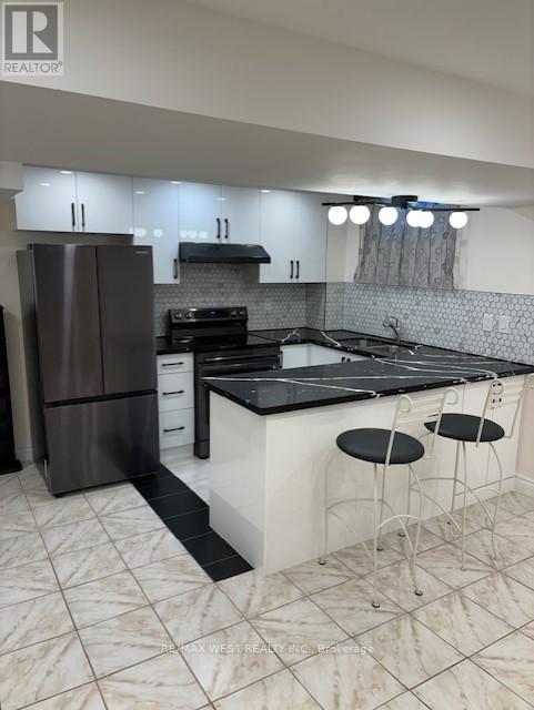 A modern kitchen with a black countertop and white cabinets.