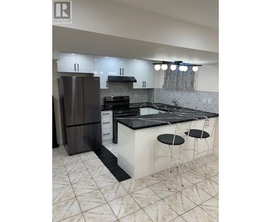 A modern kitchen with a black countertop and white cabinets.