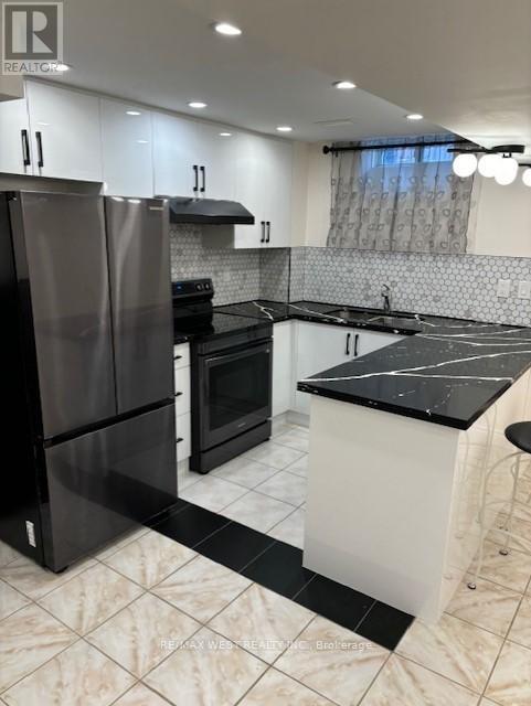 A modern kitchen with black and white appliances and a marble floor.