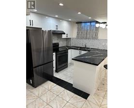 A modern kitchen with black and white appliances and a marble floor.