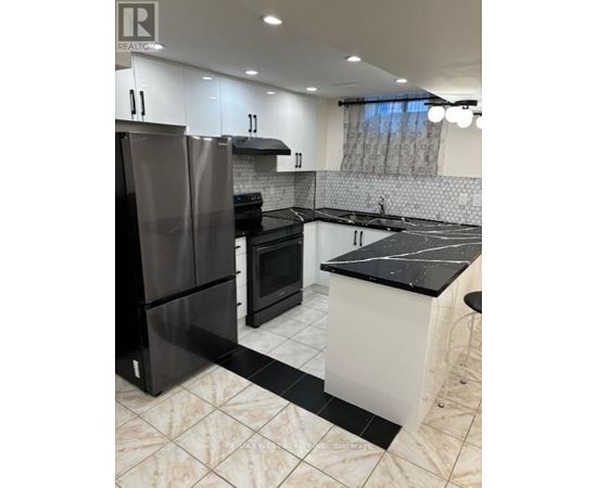 A modern kitchen with black and white appliances and a marble floor.