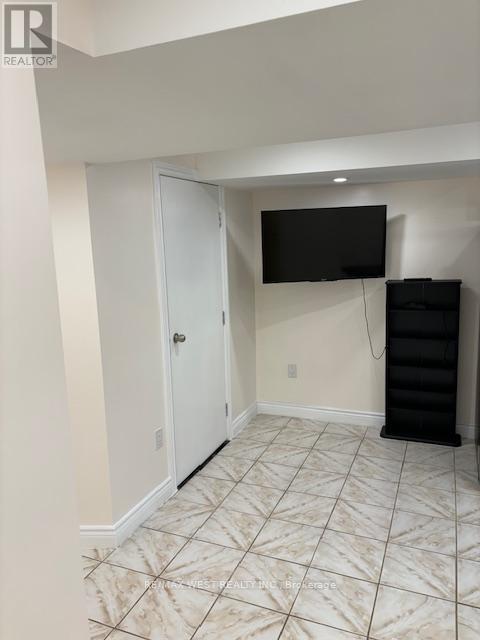 A room with a white door, a black TV mounted on the wall, and a black cabinet.