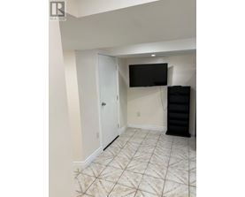 A room with a white door, a black TV mounted on the wall, and a black cabinet.