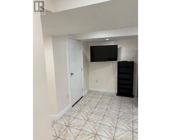 A room with a white door, a black TV mounted on the wall, and a black cabinet.
