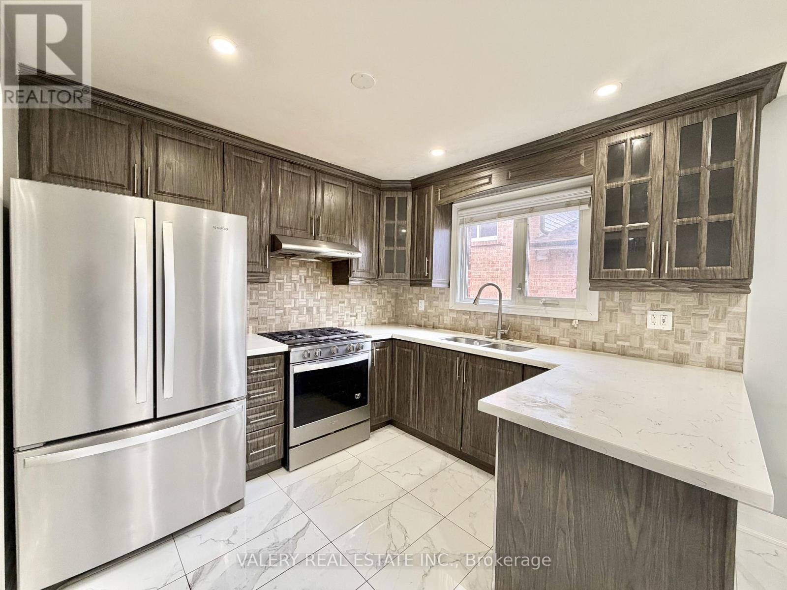 A kitchen with a refrigerator, oven, and sink.