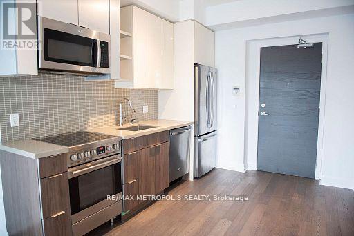 A kitchen with a stove top oven, microwave, and refrigerator.