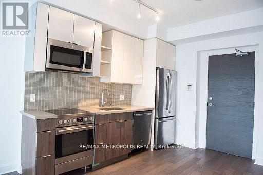A kitchen with a stove top oven, microwave, refrigerator, and sink.