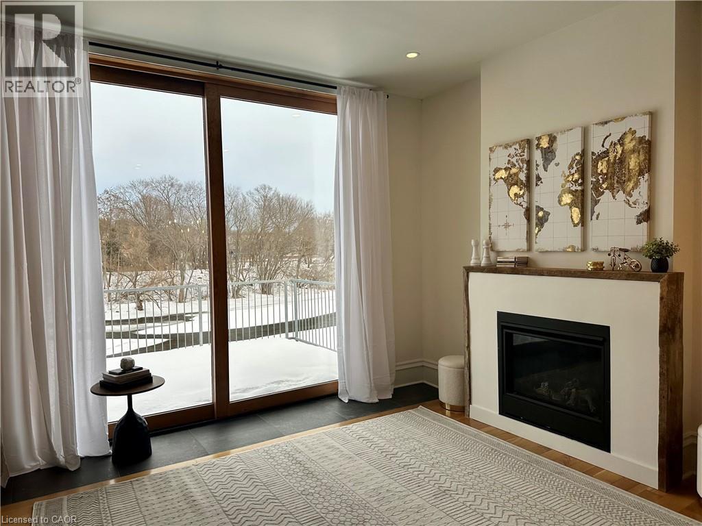 A living room with a fireplace and a view of a snowy landscape outside.