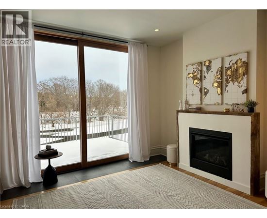 A living room with a fireplace and a view of a snowy landscape outside.