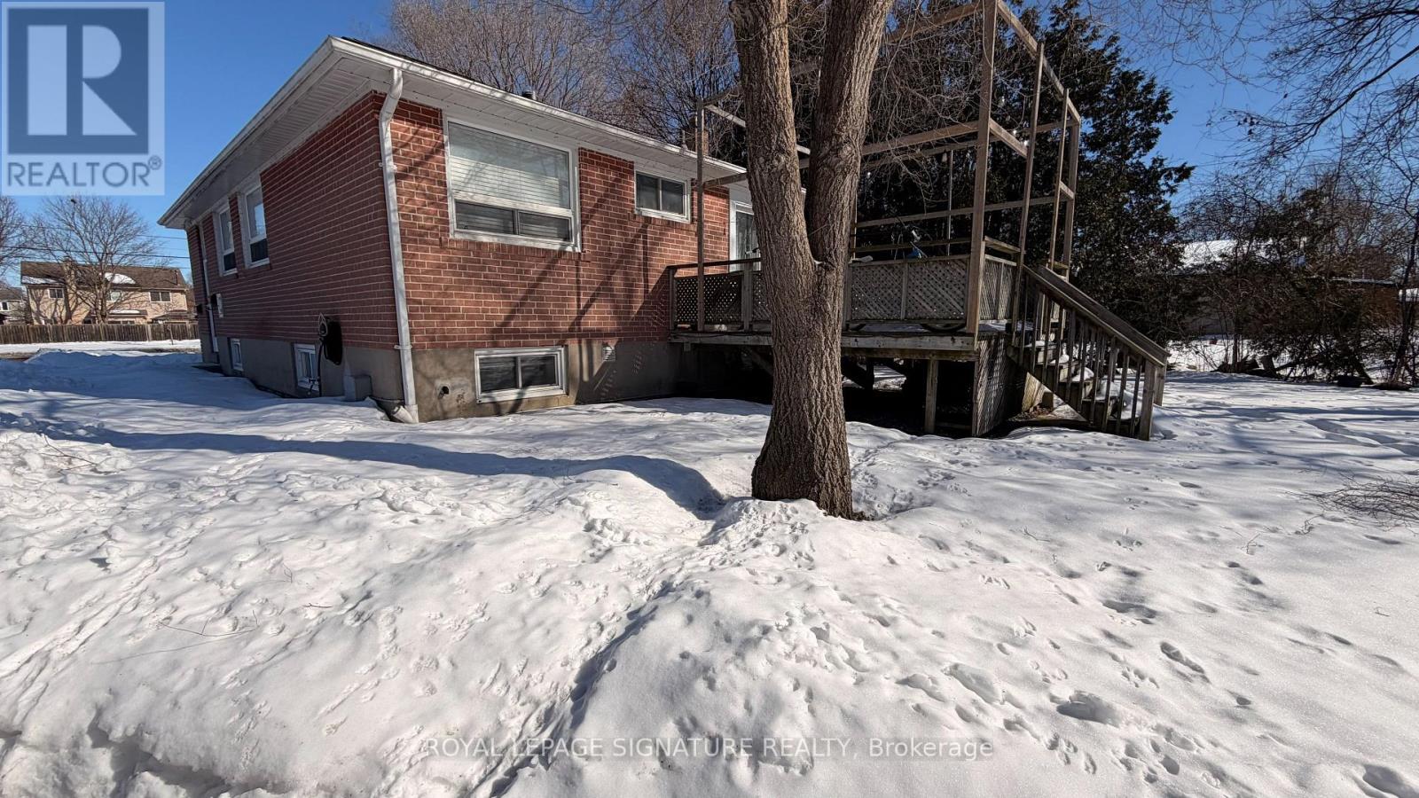 A house with a red brick exterior is surrounded by snow.